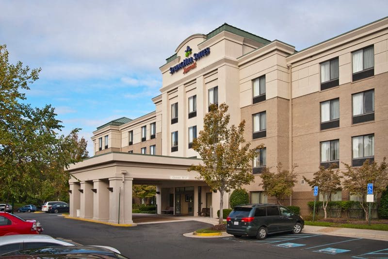 Exterior view of a modern hotel building with parked cars.