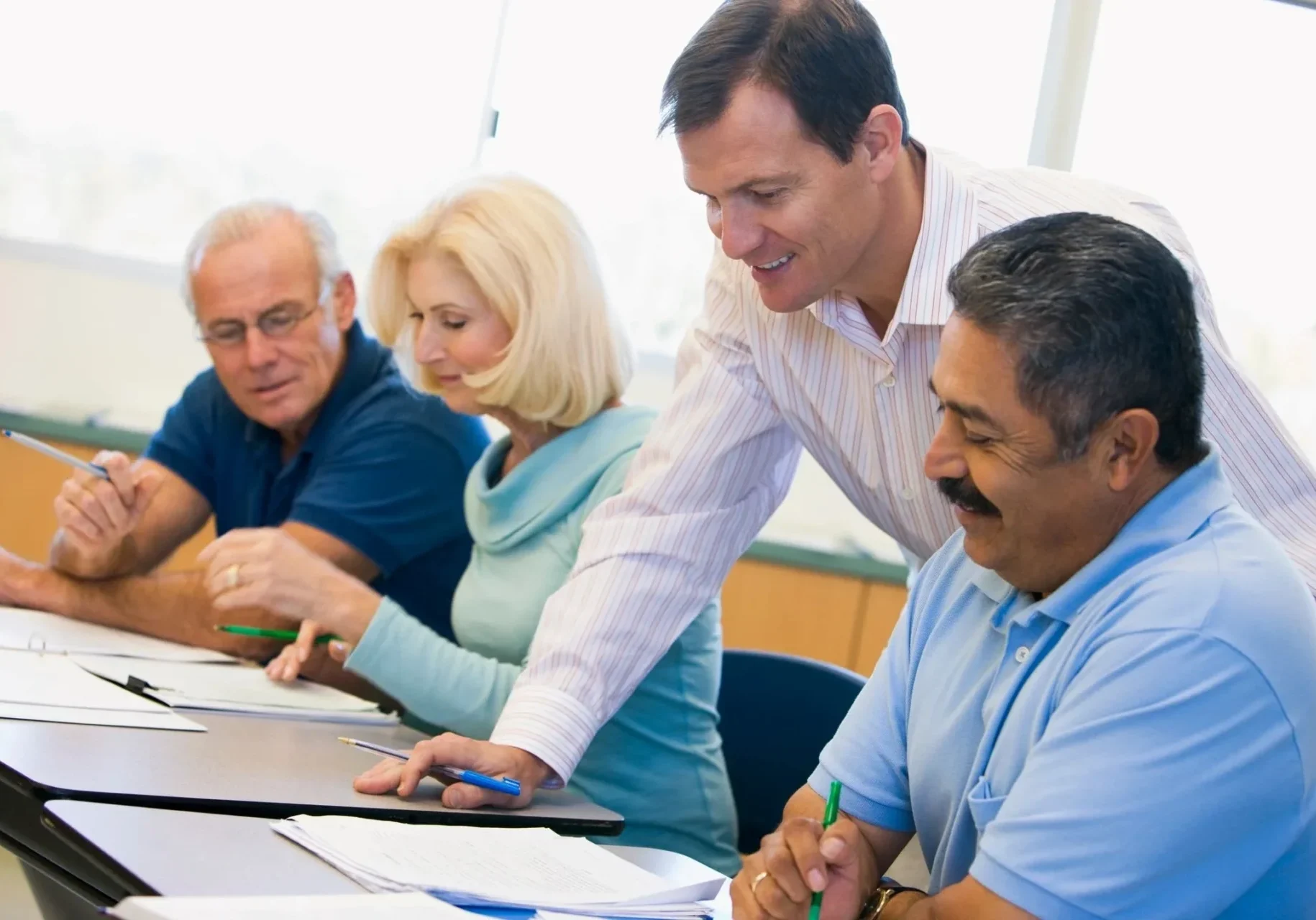A group of diverse colleagues collaborating around a table in a bright office.