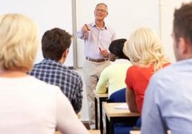 Teacher giving a lecture to attentive students in a classroom.