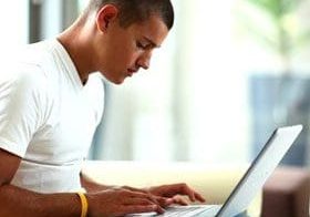 Young man focused on typing on his laptop.